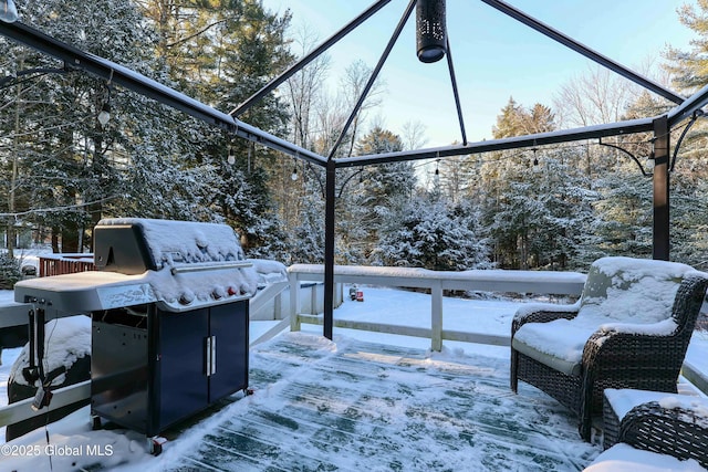 snow covered patio with a grill and a deck