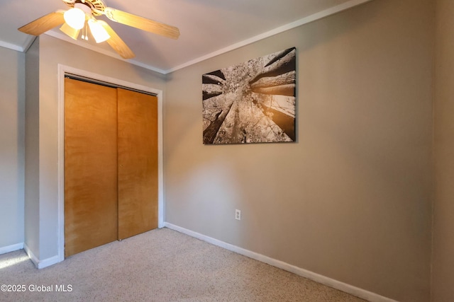 unfurnished bedroom featuring light carpet, a closet, ceiling fan, and crown molding