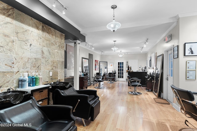 interior space with light wood-type flooring, rail lighting, crown molding, and a notable chandelier