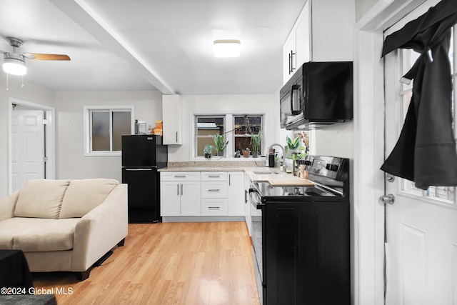 kitchen with a wealth of natural light, sink, light hardwood / wood-style flooring, white cabinets, and black appliances