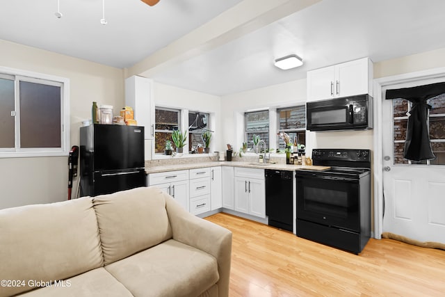 kitchen with black appliances, white cabinets, sink, and light hardwood / wood-style flooring