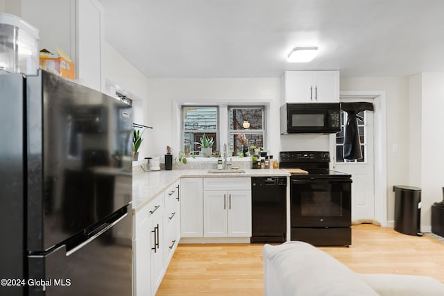 kitchen featuring light wood-type flooring, sink, white cabinetry, and black appliances