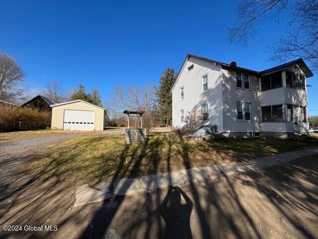 view of side of property featuring a sunroom, a garage, and an outbuilding