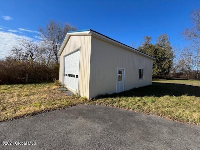 view of side of home with a yard, an outdoor structure, and a garage