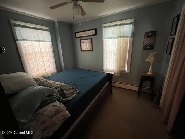 bedroom featuring ceiling fan, dark carpet, and a baseboard heating unit