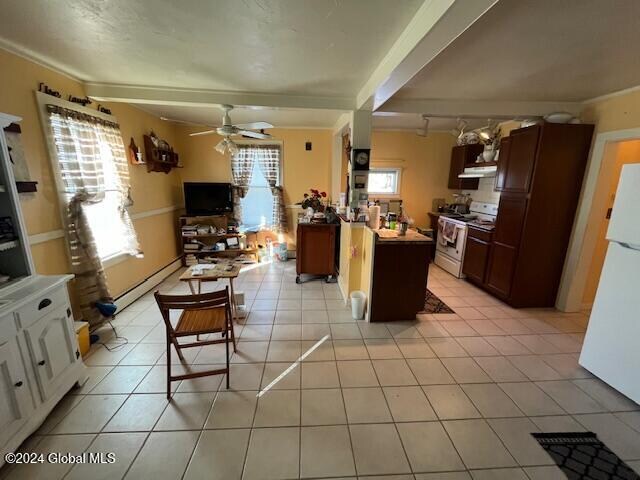 kitchen featuring light tile patterned floors, white appliances, baseboard heating, and a healthy amount of sunlight