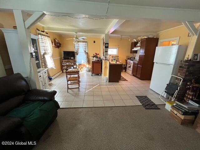 kitchen with ceiling fan, stainless steel range, a center island, white refrigerator, and light tile patterned floors