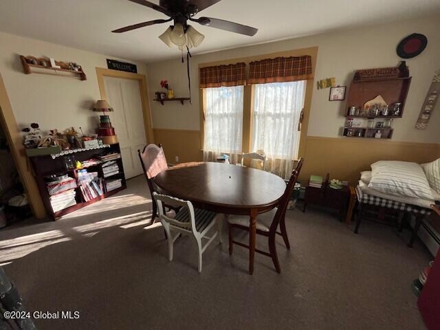 carpeted dining room with ceiling fan