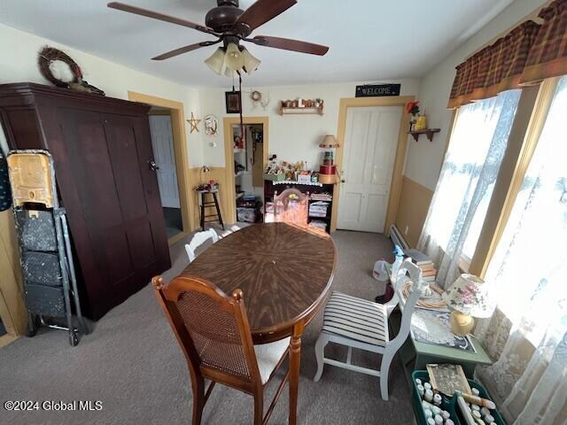 carpeted dining area with ceiling fan