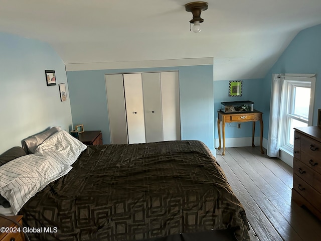 bedroom featuring hardwood / wood-style floors, a closet, and vaulted ceiling