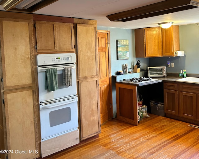 kitchen featuring light wood-type flooring, white appliances, and sink