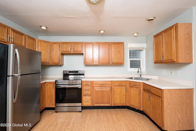 kitchen with appliances with stainless steel finishes, light hardwood / wood-style floors, and sink