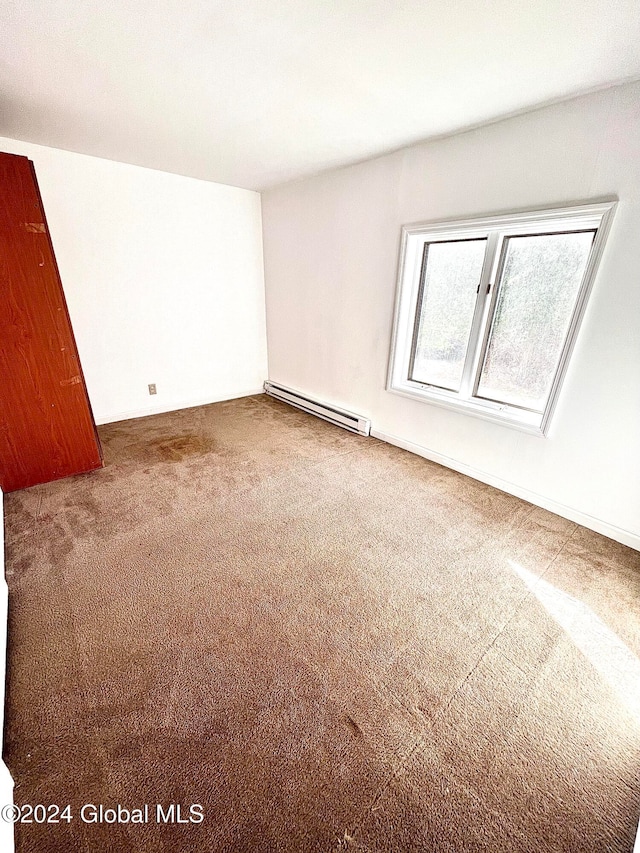 carpeted spare room with a baseboard heating unit