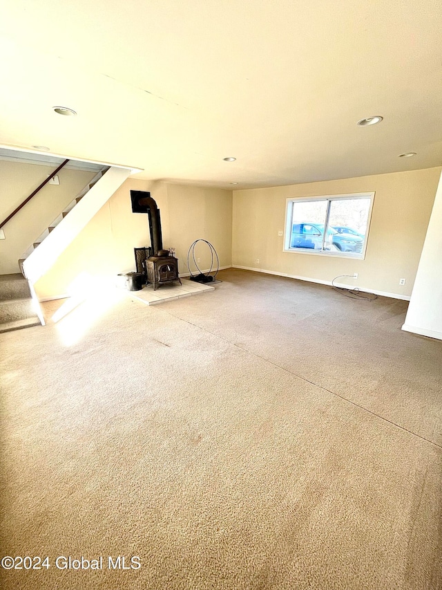 unfurnished living room with carpet and a wood stove