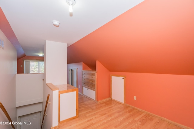 additional living space featuring lofted ceiling and light hardwood / wood-style flooring