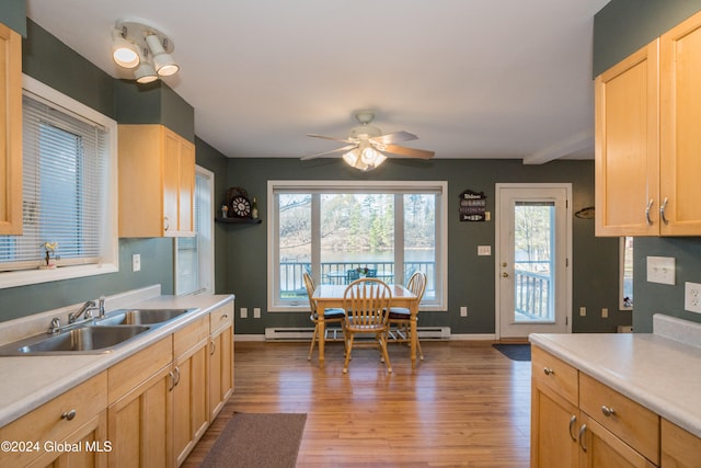 kitchen with sink, light brown cabinetry, baseboard heating, and light hardwood / wood-style floors