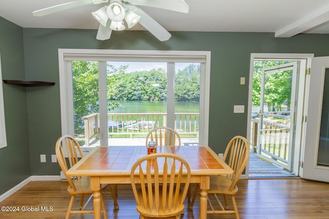 dining room with wood-type flooring, a water view, and ceiling fan