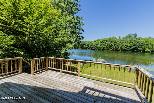 wooden deck featuring a water view and a lawn