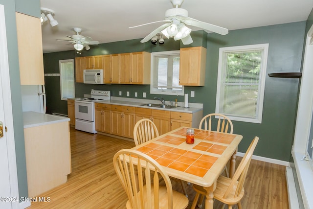 kitchen with white appliances, light brown cabinetry, sink, and light hardwood / wood-style flooring