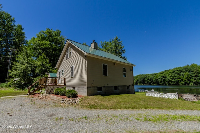 view of side of home featuring a deck with water view and a yard