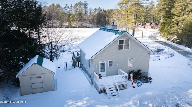 snow covered rear of property with a storage unit