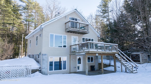 snow covered house with a balcony and a deck