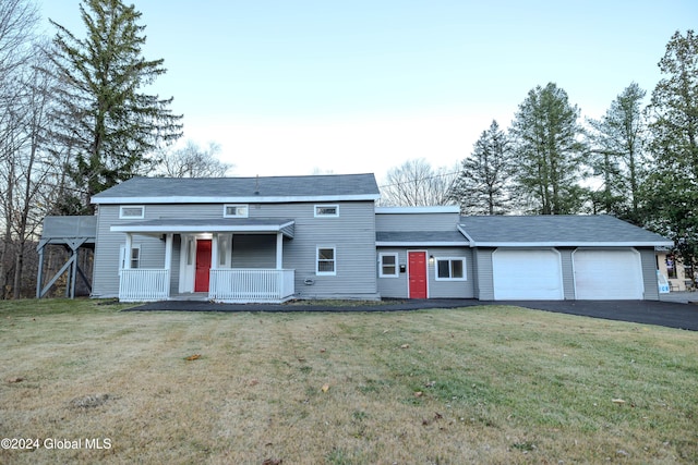 view of front of house featuring covered porch, a garage, and a front yard