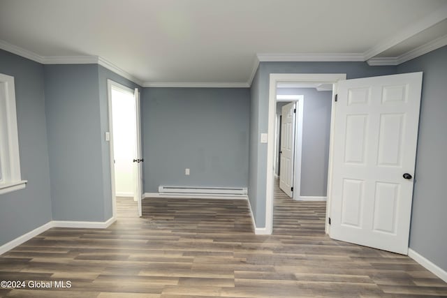 empty room with dark hardwood / wood-style flooring, ornamental molding, and a baseboard heating unit