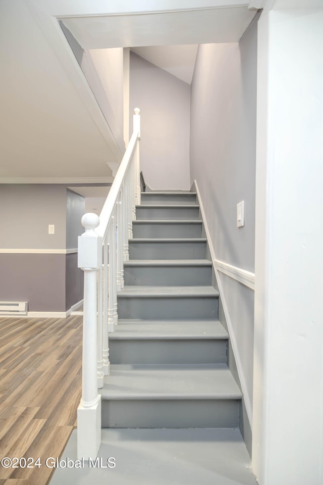 staircase with hardwood / wood-style floors and a baseboard heating unit