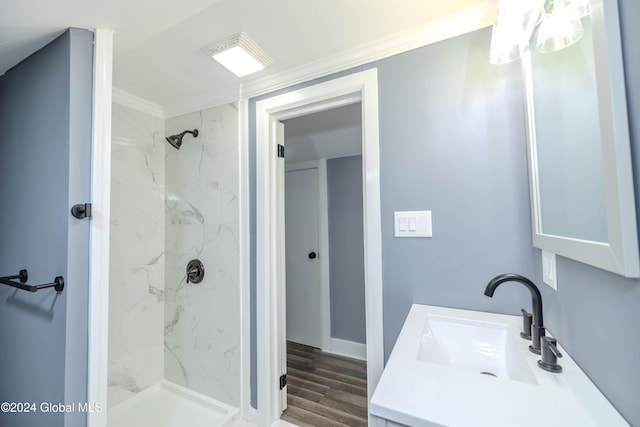 bathroom with vanity, wood-type flooring, tiled shower, and ornamental molding