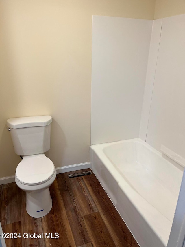 bathroom with a bathtub, toilet, and wood-type flooring