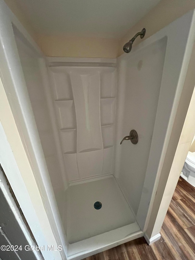 bathroom featuring a shower, toilet, and hardwood / wood-style flooring