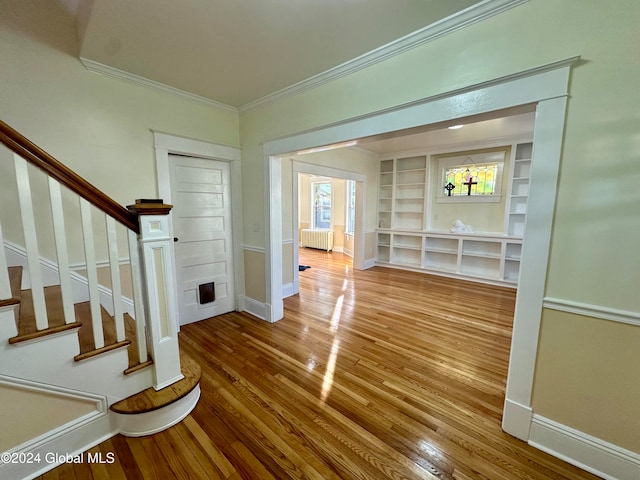 foyer with crown molding, radiator heating unit, and hardwood / wood-style flooring