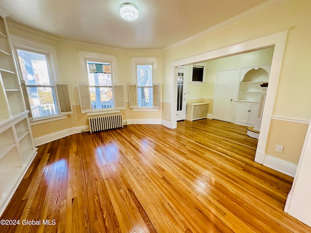 unfurnished living room with radiator heating unit, light hardwood / wood-style floors, a wealth of natural light, and crown molding