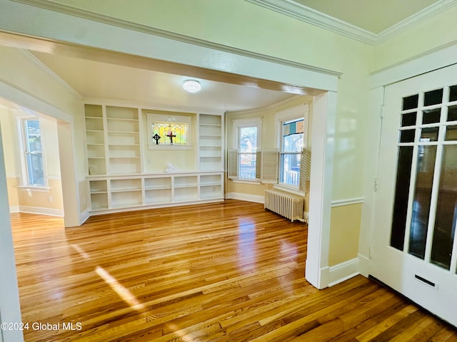 interior space with radiator heating unit, built in shelves, crown molding, and wood-type flooring