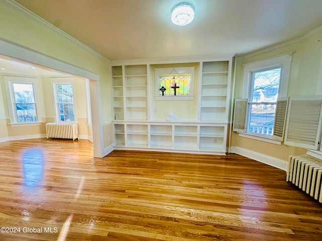 interior space with hardwood / wood-style flooring, built in shelves, radiator heating unit, and crown molding