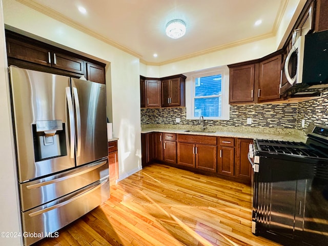 kitchen featuring backsplash, sink, light stone countertops, light hardwood / wood-style floors, and stainless steel appliances