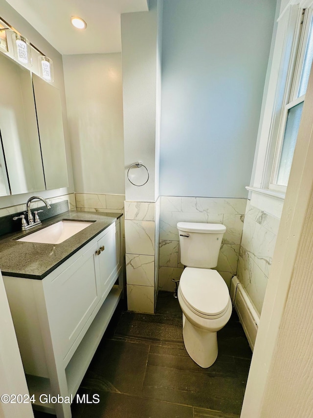 bathroom featuring vanity, toilet, and tile walls