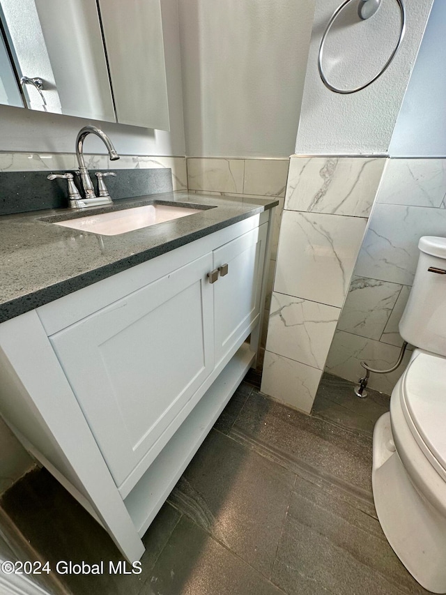 bathroom with vanity, tile walls, and toilet