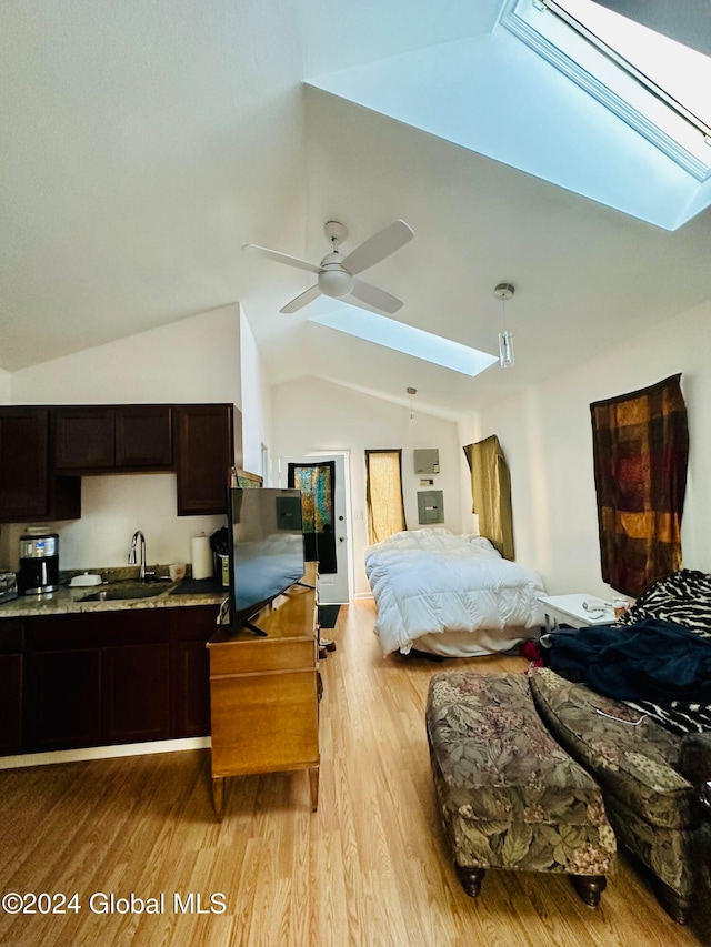 bedroom featuring vaulted ceiling with skylight, light hardwood / wood-style floors, ceiling fan, and sink