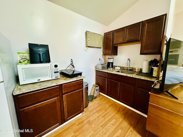 kitchen with light hardwood / wood-style floors, dark brown cabinetry, lofted ceiling, and sink