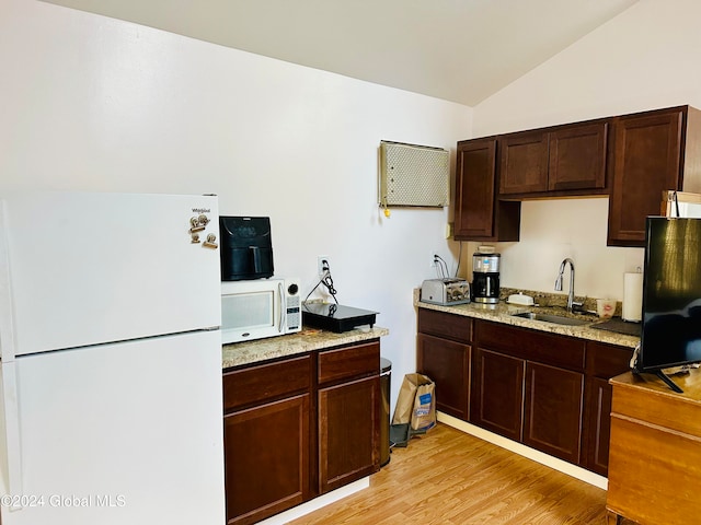 kitchen featuring lofted ceiling, white appliances, sink, light stone countertops, and light wood-type flooring