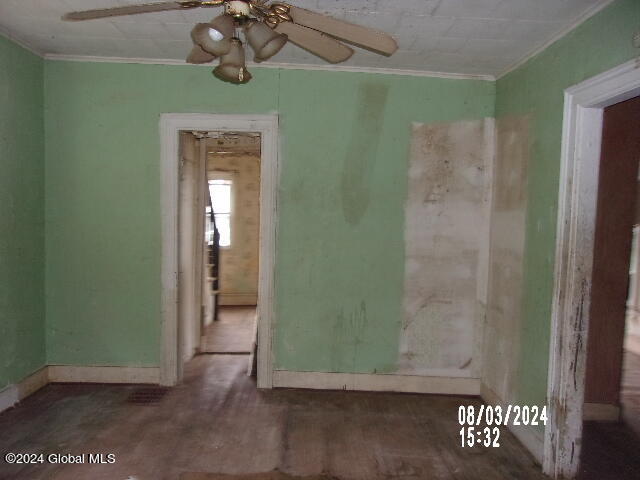 unfurnished room with ceiling fan and crown molding