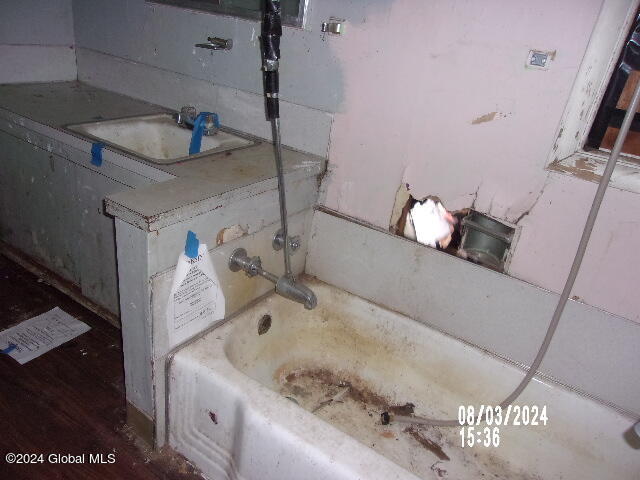 bathroom with hardwood / wood-style floors, sink, and a bath