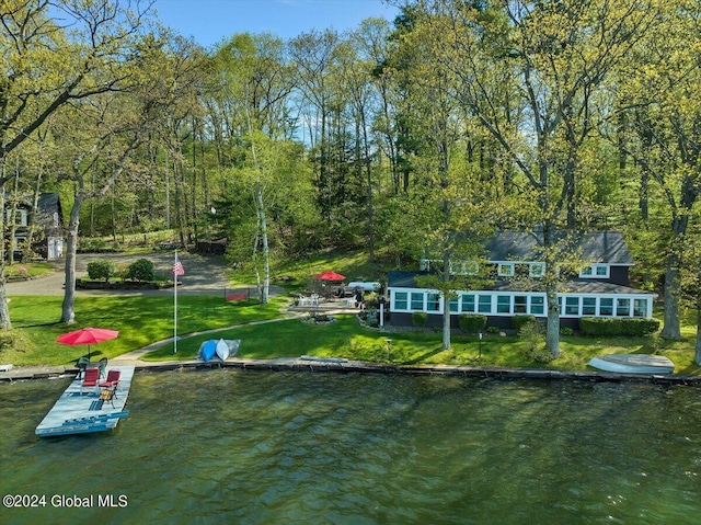 back of property with a lawn and a water view