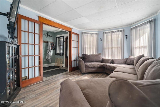 living room with a paneled ceiling, crown molding, and wood-type flooring