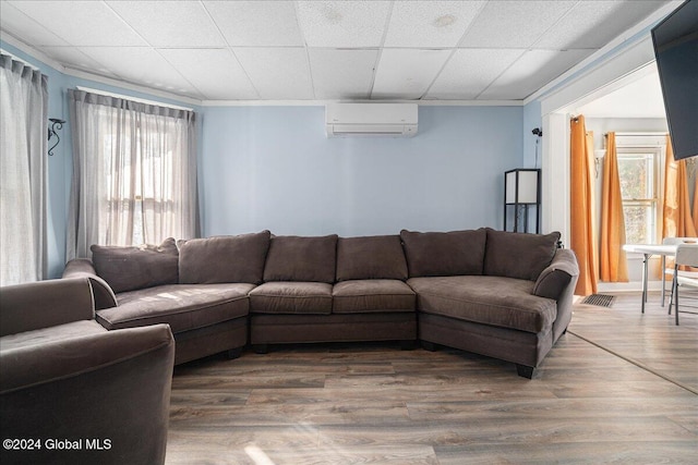 living room featuring wood-type flooring, a paneled ceiling, an AC wall unit, and a wealth of natural light