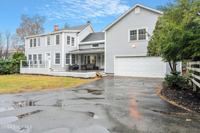 rear view of property featuring a yard, covered porch, and a garage