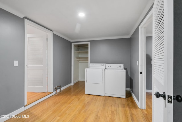 laundry area with washing machine and clothes dryer, crown molding, and light hardwood / wood-style flooring