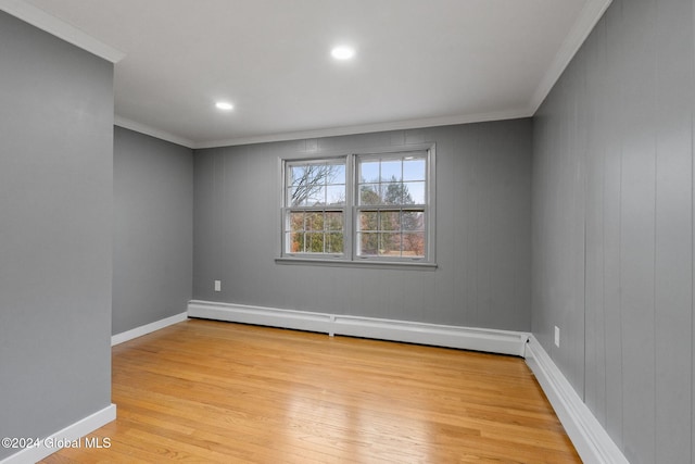 unfurnished room featuring light wood-type flooring, crown molding, wooden walls, and a baseboard heating unit